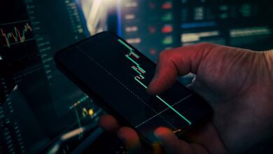 trader analyzing stock market data on smartphone and phone