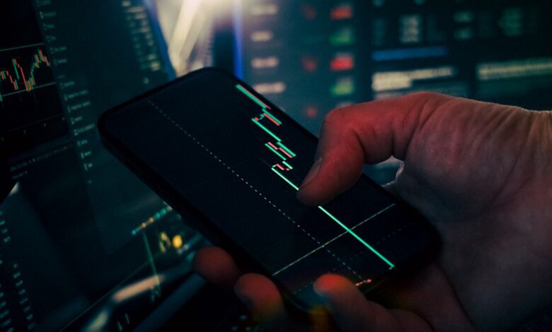 trader analyzing stock market data on smartphone and phone
