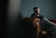 a man holds his head while sitting on a sofa