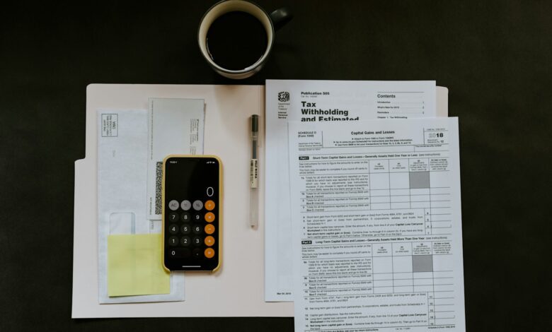black android smartphone near ballpoint pen, tax withholding certificate on top of white folder