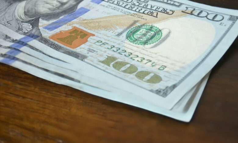 here's a short caption: hundred dollar bills stacked on a table.