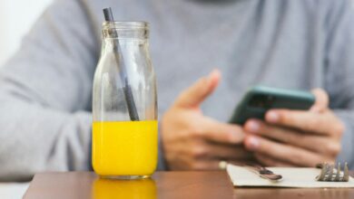a person holding a phone and a glass of liquid