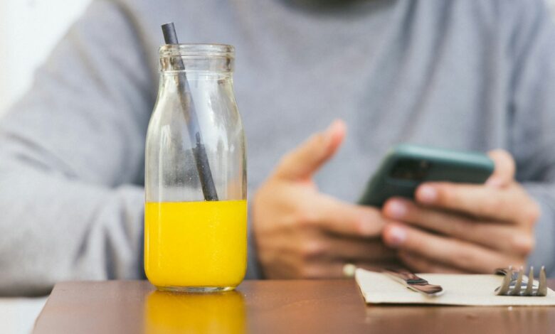 a person holding a phone and a glass of liquid