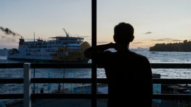 a man is looking out at a boat in the water