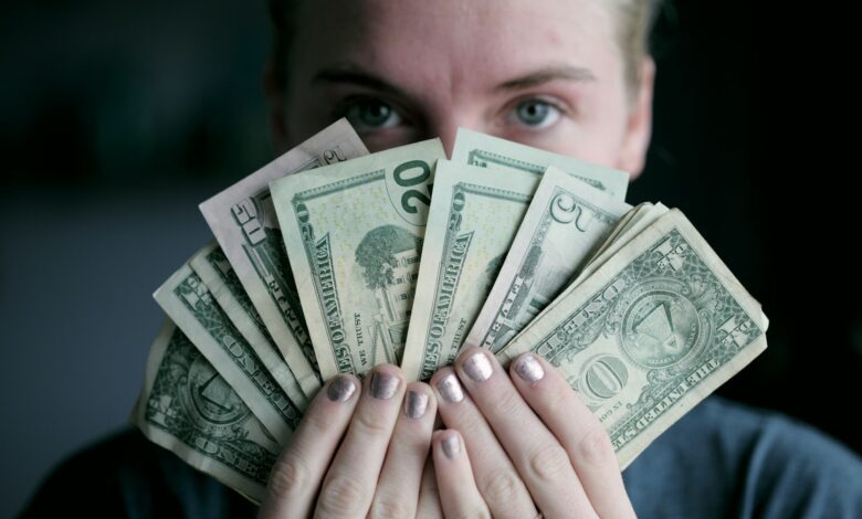 person holding fan of u.s. dollars banknote