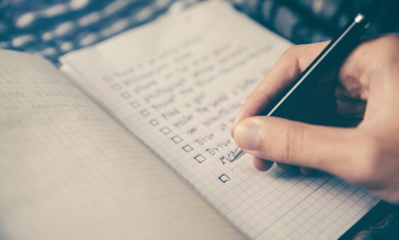 person writing bucket list on book