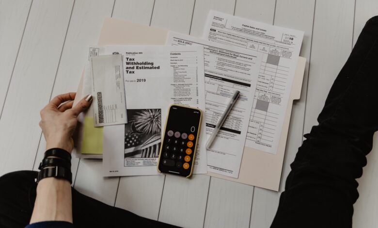 person holding paper near pen and calculator