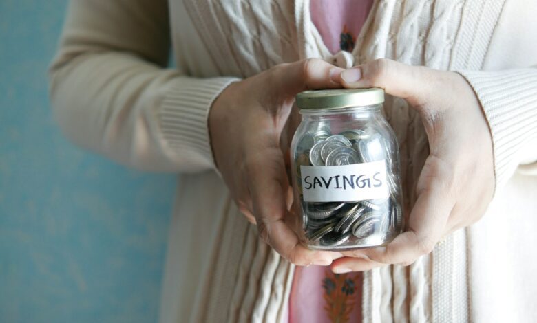 a woman holding a jar with savings written on it